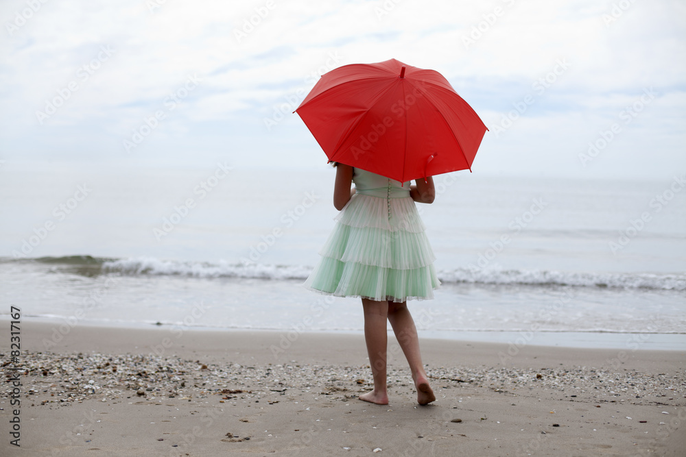 Niña con sombrilla roja de espaldas en la playa Stock Photo | Adobe Stock