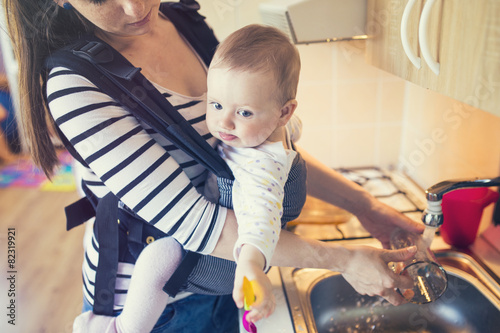 Obraz na płótnie Young mother washing up dishes with her little daughter
