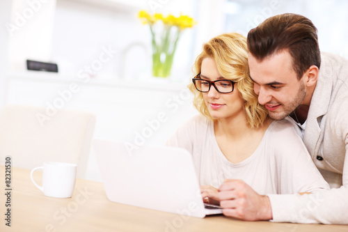 Happy couple using laptop at home