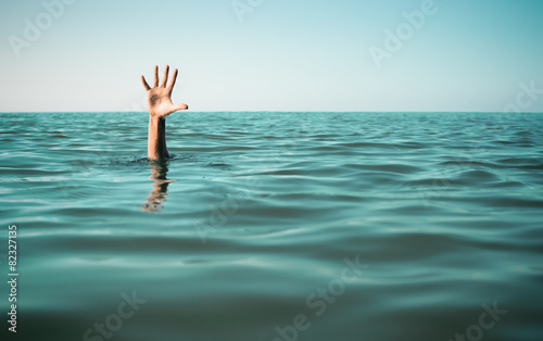Hand in sea water asking for help. Failure and rescue concept.