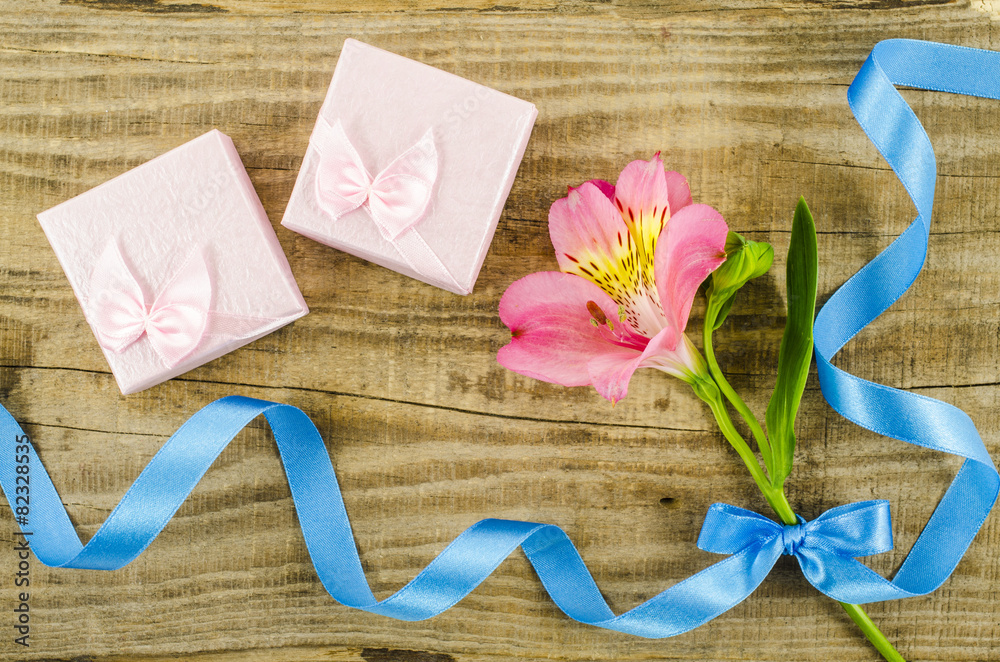 Gift boxes with flower and ribbon on wooden table