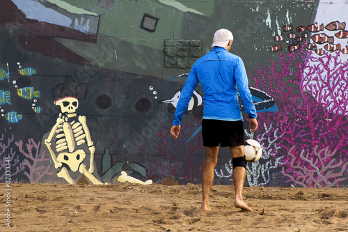football soccer player with a skeleton and fish on the beach