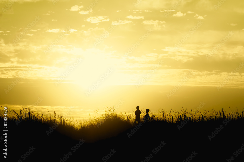 children playing on beach dunes at sunset silhouette