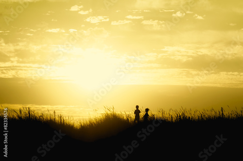 Fototapeta Naklejka Na Ścianę i Meble -  children playing on beach dunes at sunset silhouette