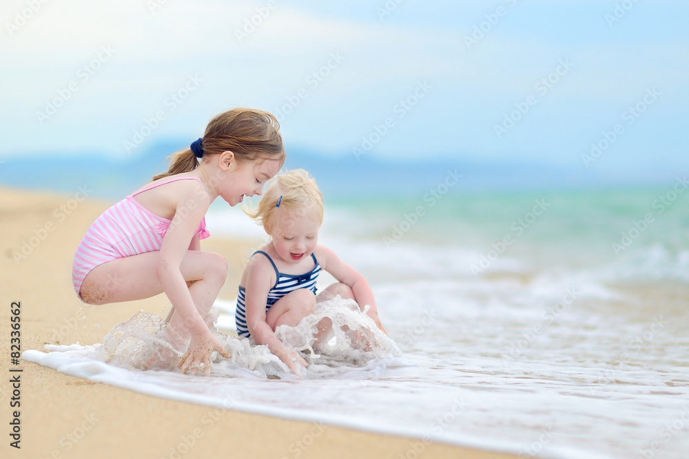 Two little sisters having fun on a beach Two little sisters having fun on a beach
