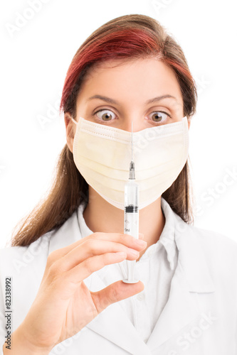 Young doctor wearing surgical mask and holding a syringe