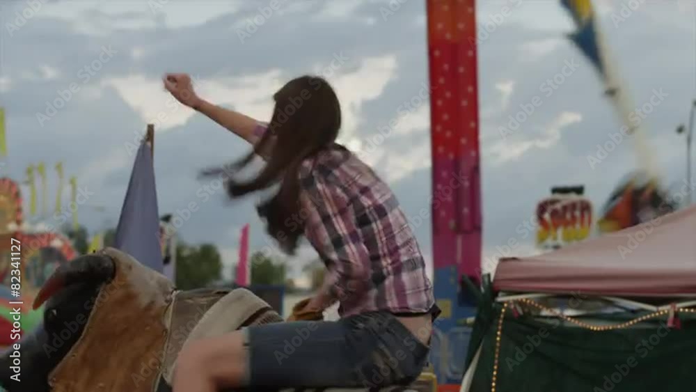 Time lapse medium shot of teenage girl riding mechanical bull at amusement park / Salt Lake City, Utah, United States