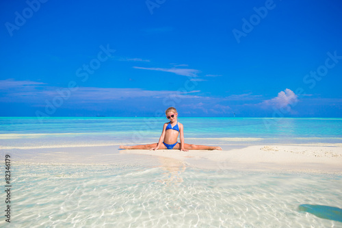 Adorable little girl sitting on the splits at beach