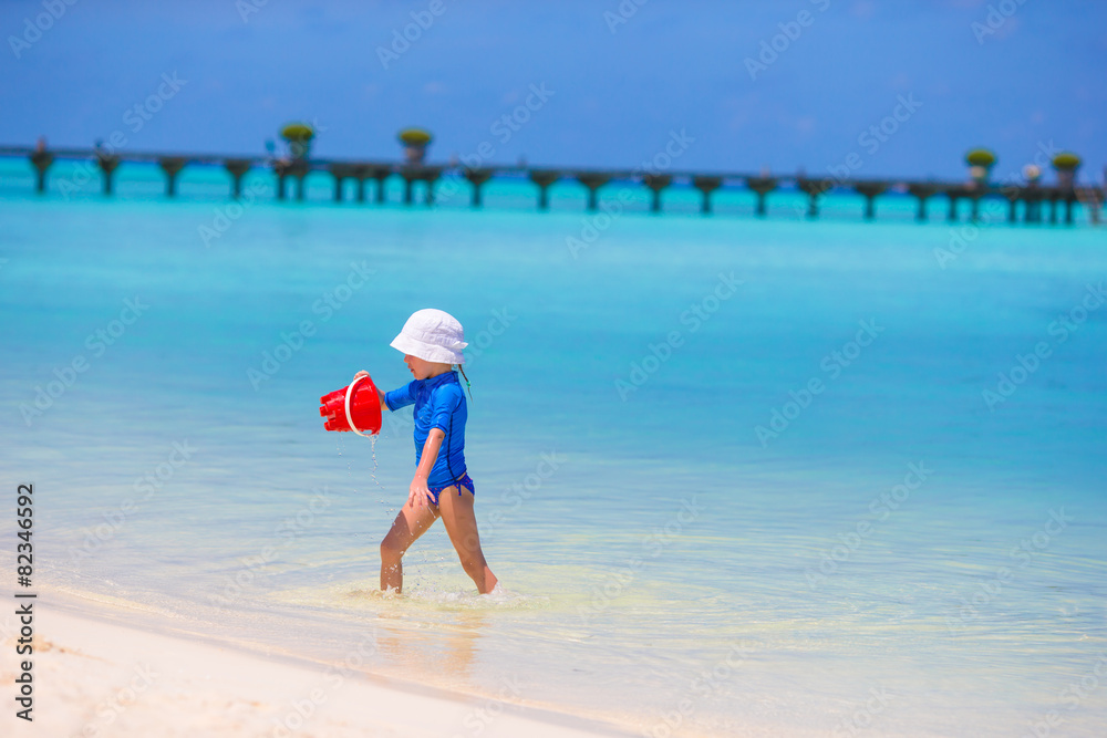 Adorable little girl playing with beach toys during tropical