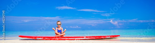 Photography Little girl in yoga position meditating on surfboard