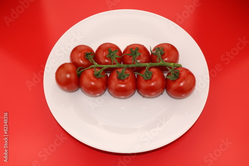 Isolated cluster of fresh ripe red cherry tomatoes © RukiMedia