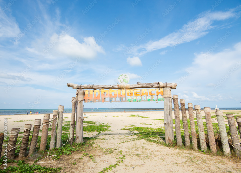 An image of wooden gate on the beach in blue sky and some clouds