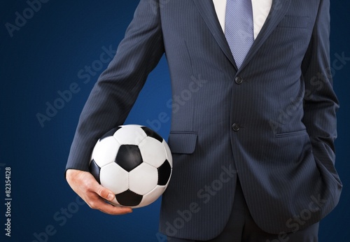 Soccer. Elegant businessman holding a soccer ball, close up