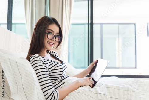 Portrait of a beautiful girl using a digital tablet in bed