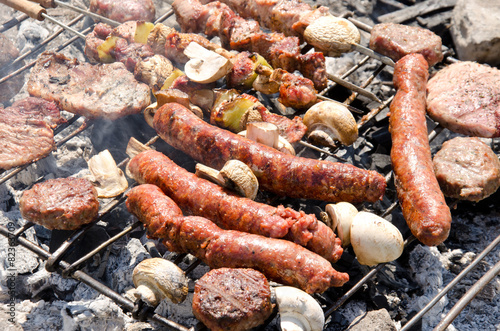 Beef steaks and sausages cooking in open flame on barbecue grill