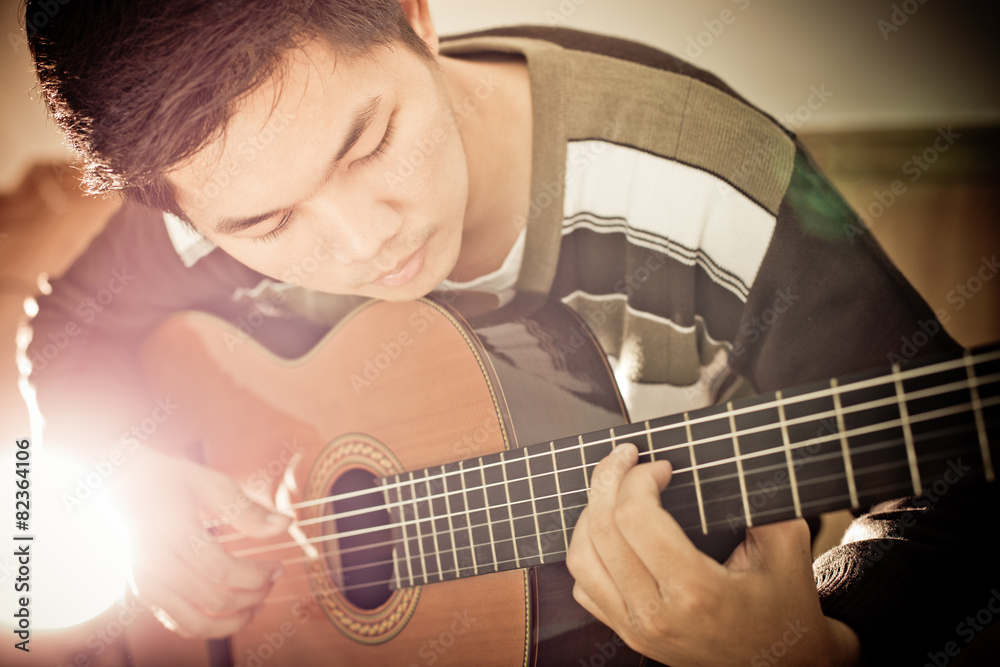 Fototapeta premium Practicing in playing guitar. Handsome young men playing guitar