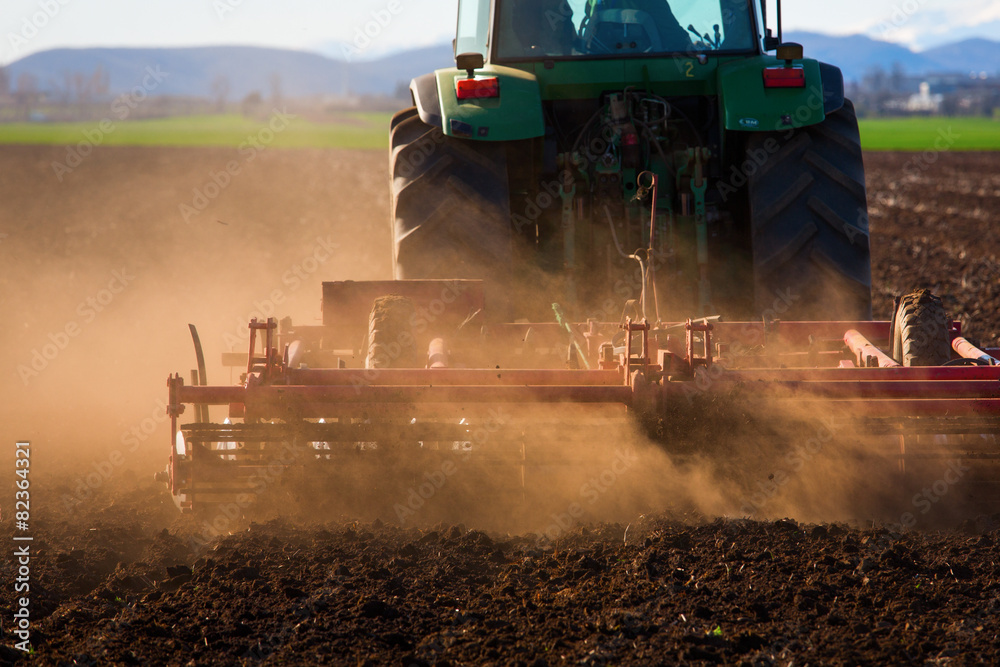 Obraz premium Tractor in sunset plowing the field