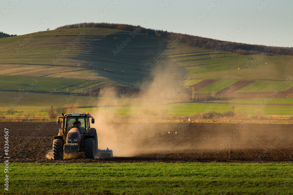 Fototapeta premium Tractor in sunset plowing the field