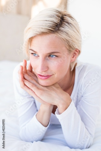 Smiling blonde woman lying on the bed