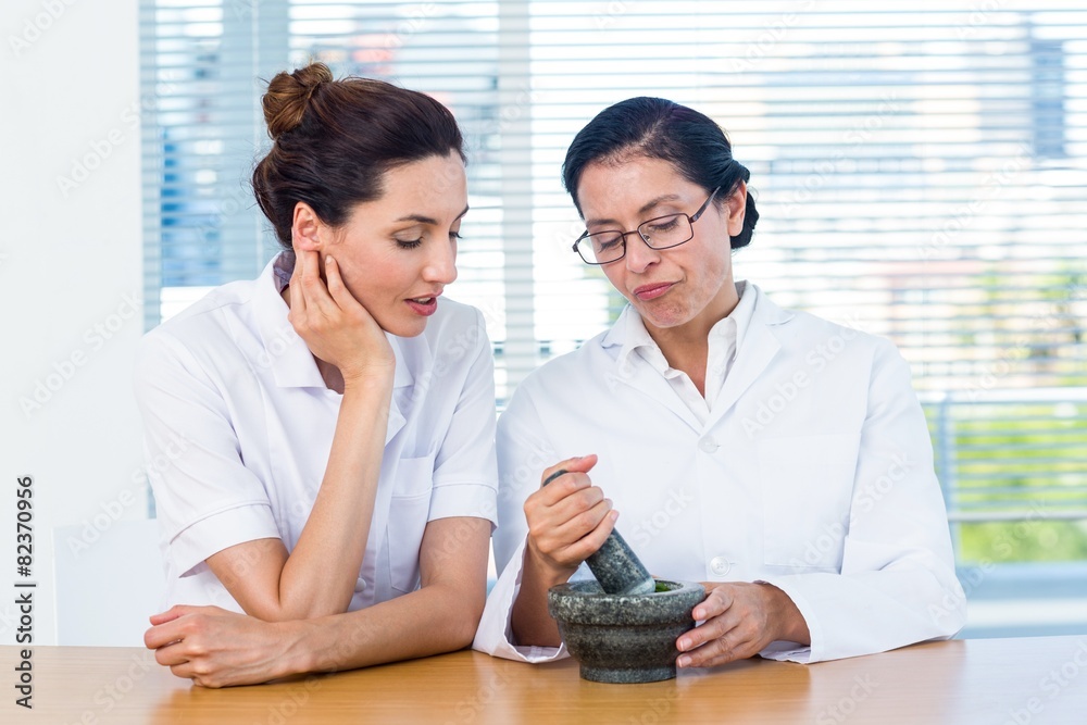 Scientists mixing herbs with pestle and mortar Scientists mixing herbs with pestle and mortar