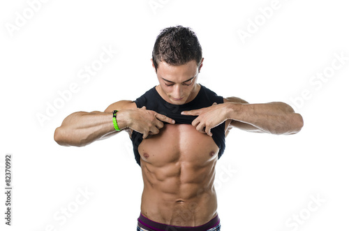 Handsome, fit young man pulling up t-shirt revealing abs