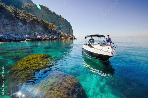 Woman relaxing on a boat in the sea near the rocky shore.