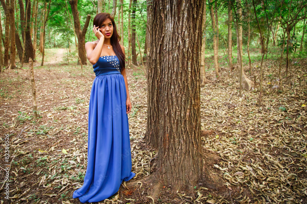 atractive latin woman using phone at forest with blue dress