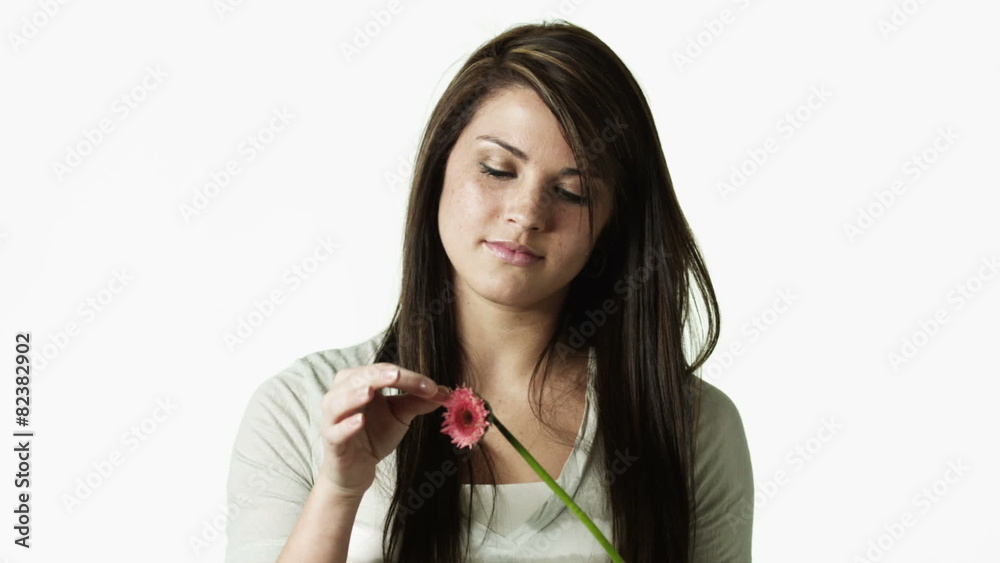 MS Portrait of young woman picking flower apart against white background / Orem, Utah, USA MS Portrait of young woman picking flower apart against white background / Orem, Utah, USA