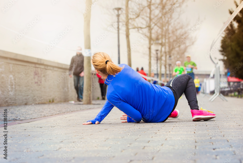 Young woman running in a city competition falling on the ground