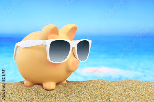 Summer piggy bank with sunglasses on beach © viperagp