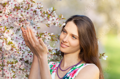 Beautiful brunette woman in blooming orchard