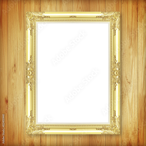 Antique gold frame on wooden wall ;. Empty picture frame on whit