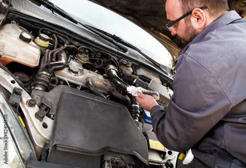 Auto mechanic checks the oil on a car being repaired