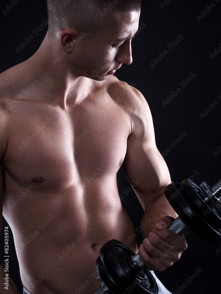 Man with bare chest lifting dumbbells isolated black background.