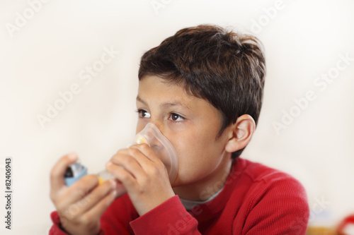 Young boy using inhaler on white background