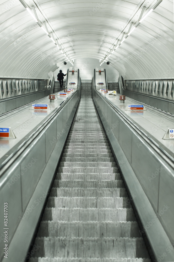 Escalator facing down with one anonymous commuter Escalator facing down with one anonymous commuter