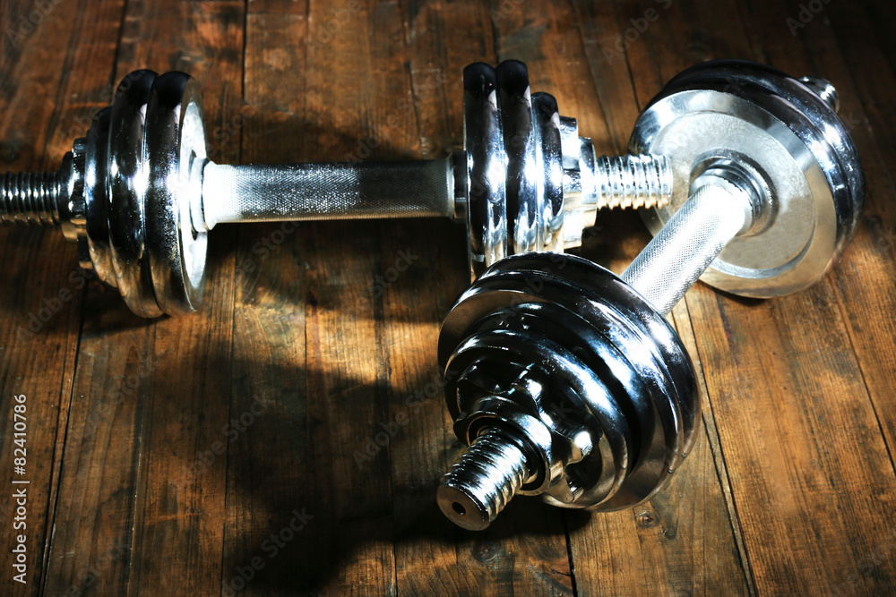 Dumbbells on wooden floor, on dark background Dumbbells on wooden floor, on dark background