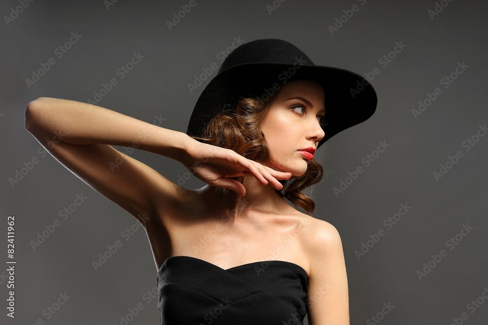 Portrait of beautiful model in black dress and hat on gray background Portrait of beautiful model in black dress and hat on gray background