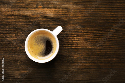 Cup of coffee on wooden table, top view