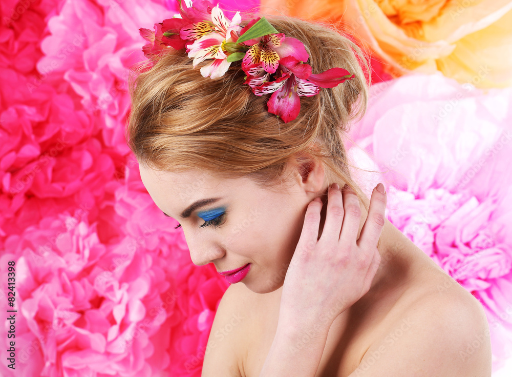 Portrait of young woman with flowers in hair on bright pink background Portrait of young woman with flowers in hair on bright pink background