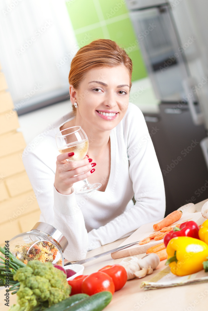 Portrait of young woman in kitchen with glass of white wine