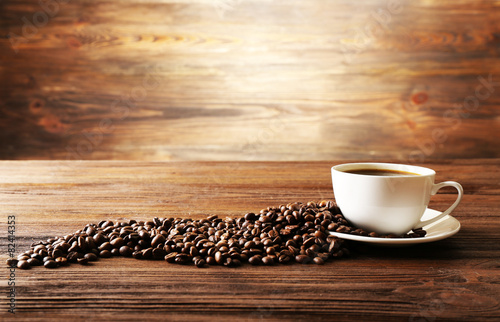 Cup of coffee with grains on wooden background