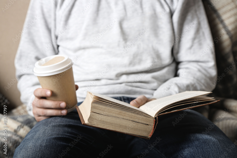 Fototapeta premium Young man reading book, close-up, on light background
