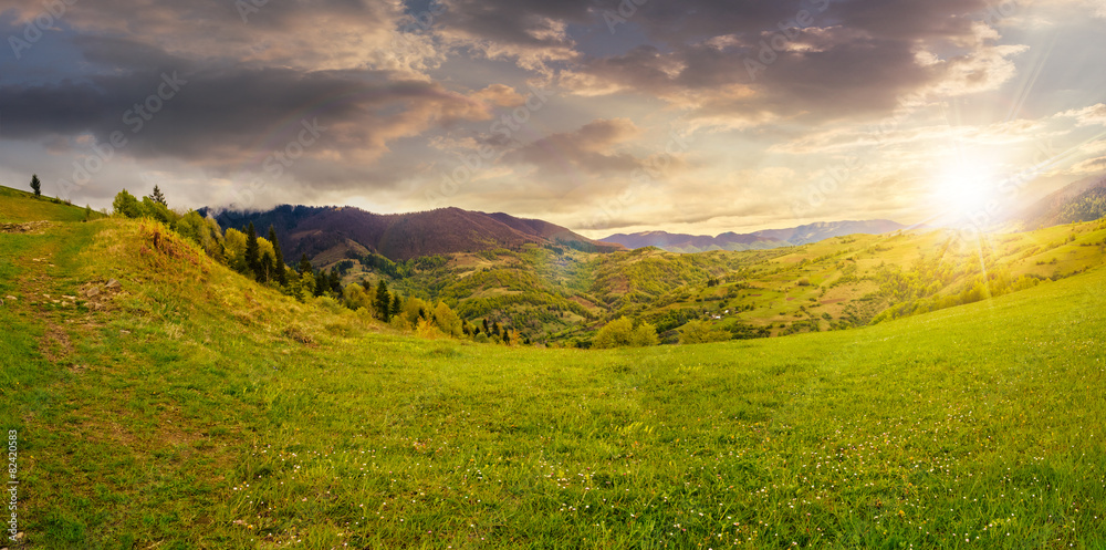 Obraz premium village on hillside meadow at sunset