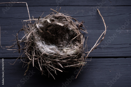 Empty straw nest with twigs on a wooden background.