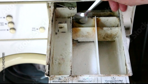 Man cleans clogged and filthy laundry machine detergent tray