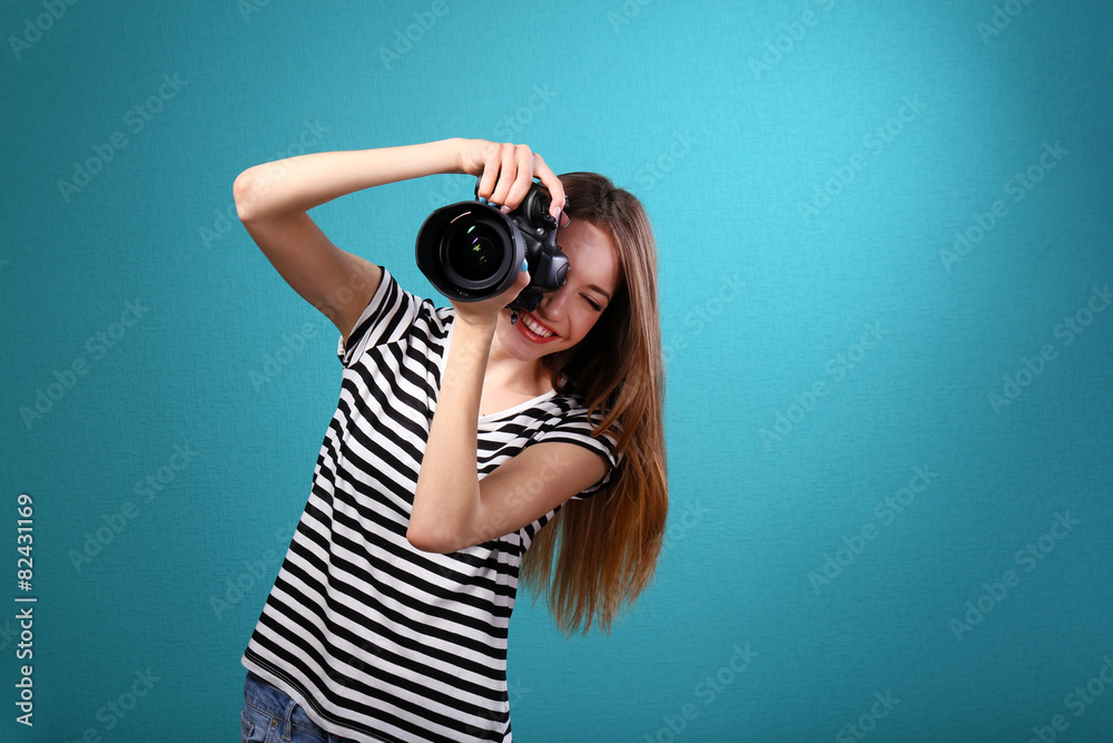 Young female photographer taking photos on blue background Young female photographer taking photos on blue background