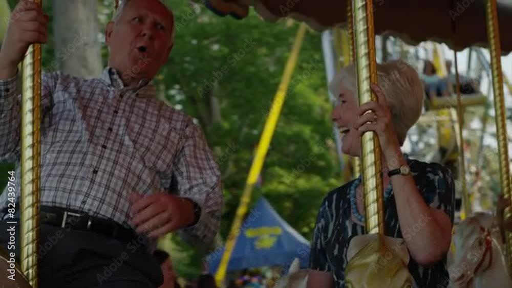 Close up of senior couple riding carousel at carnival / American Fork, Utah, United States