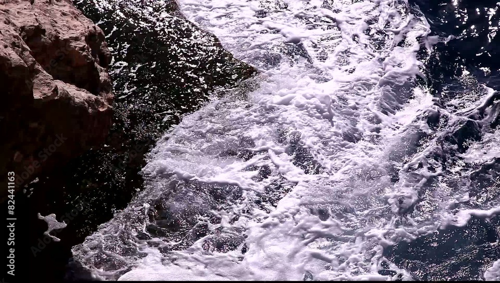 Sea waves hit rocks and beach