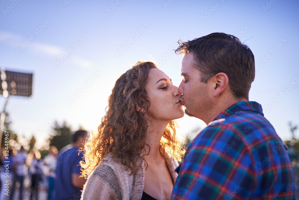 couple kissing in crowd at sunset